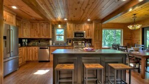 Une cuisine de style rustique, avec des éléments en bois, un îlot central, des appareils électroménagers intégrés et un coin repas.
