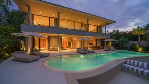 Une maison moderne dotée d’une piscine, d’un espace salon extérieur et d’un escalier menant à un balcon.