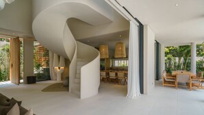 Un intérieur moderne avec un escalier en colimaçon, un coin repas et de grandes fenêtres.