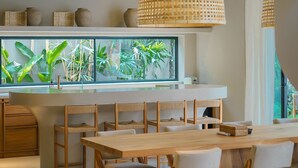 Une cuisine moderne dotée d’une grande fenêtre, de meubles en bois et de lampes suspendues en osier.