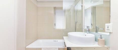 A modern bathroom with a bathtub, a sink, and a mirror.