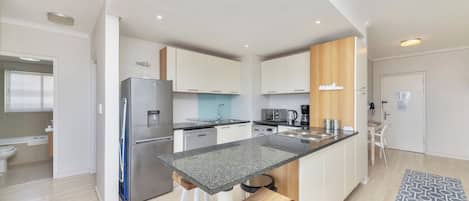 A modern kitchen with a central island, stainless steel appliances, and white cabinetry.
