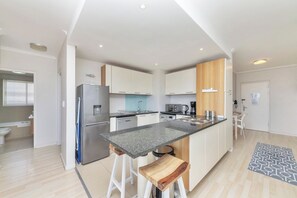 Una cocina moderna con una isla central, electrodomésticos de acero inoxidable y armarios blancos.