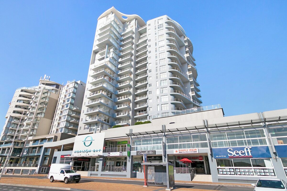 A modern high-rise hotel with multiple balconies, a ground-level cafe, and a Seeff store.