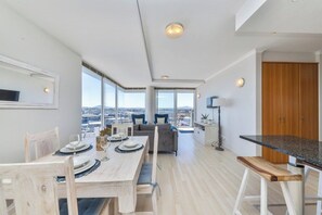 Un comedor moderno con una mesa de madera dispuesta para cuatro personas, un sofá y vistas a la ciudad.