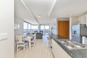 A modern kitchen with a central island, a dining area with a view, and a large window.