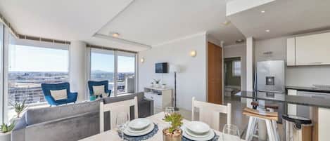 A modern dining area with a table set for four, a sofa, and a city view.