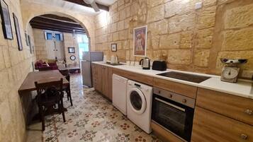 Una cocina compacta con lavadora, un lavamanos y armarios de madera.