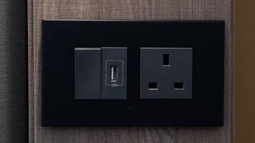 A black electrical outlet with a USB port and a standard two-prong outlet on a textured wall.