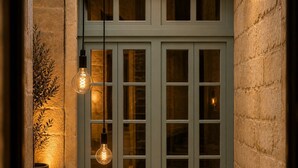 A window with multiple panes, a potted plant to the left, and two hanging light fixtures. - Mulberry Suites by The LVH Collection  (Valletta)