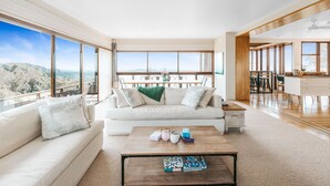 A spacious living room with a large window, a sofa, a coffee table, and a view of the outdoors.