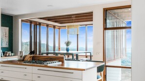 A modern kitchen with large windows, a dining area, and a view of the mountains.