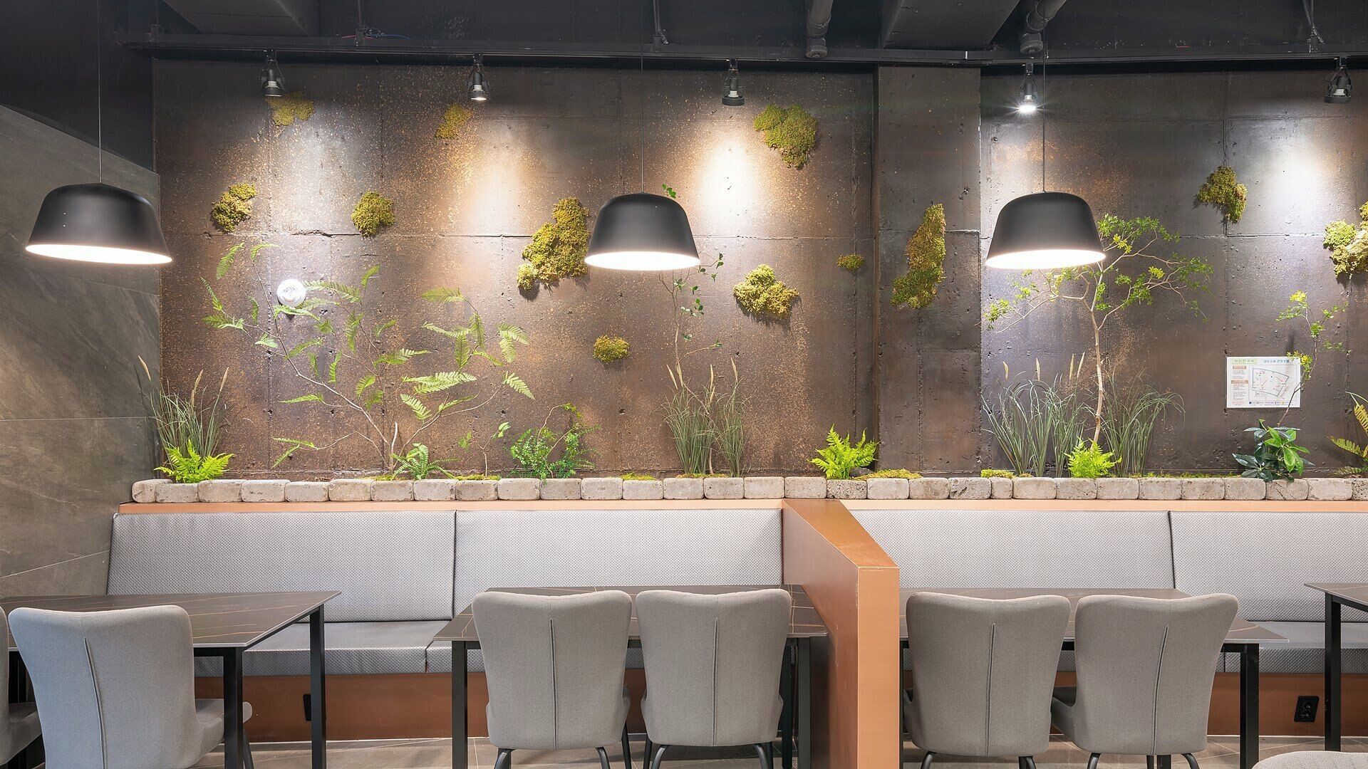 A modern indoor seating area with a long bench, multiple chairs, and pendant lighting.