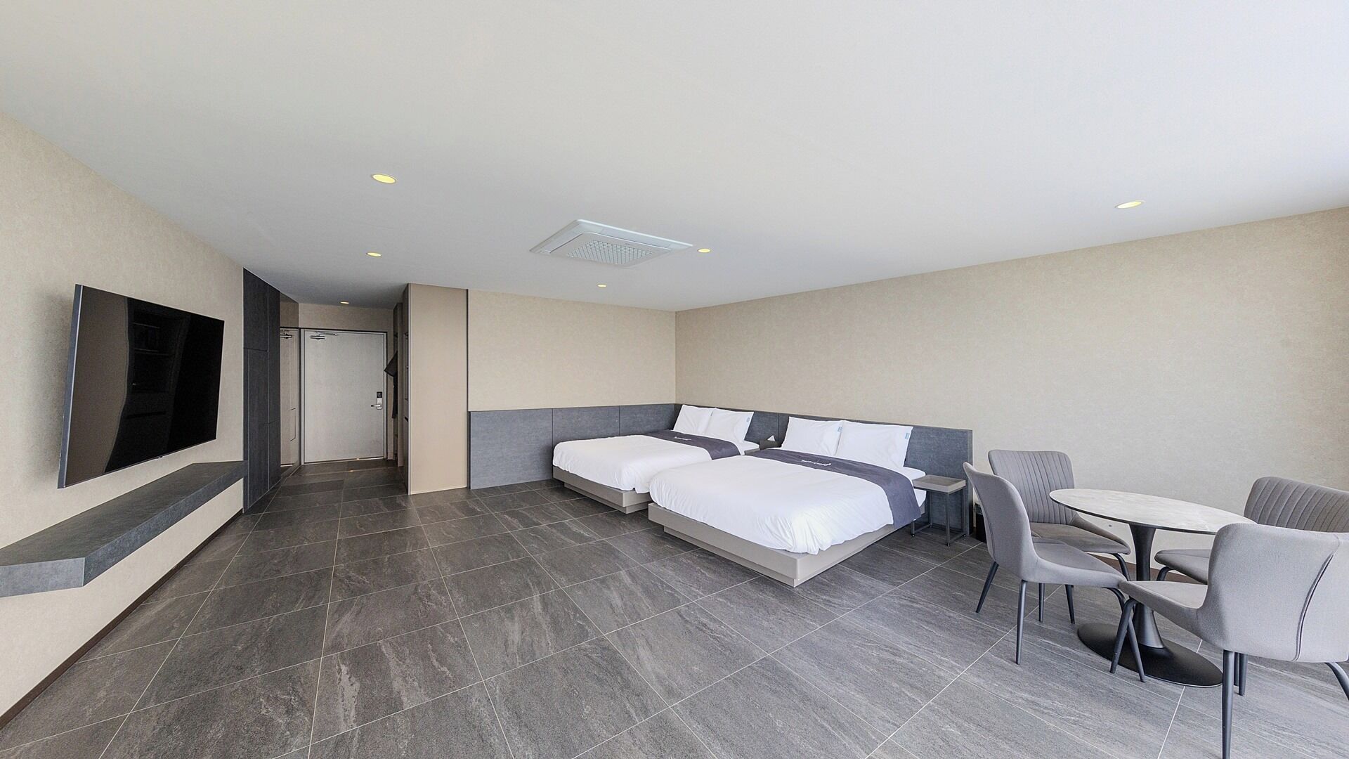 Una habitación de hotel moderna con dos camas, un televisor, un escritorio y una silla.