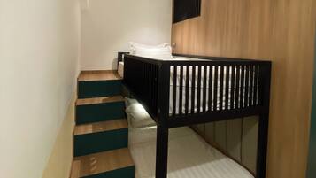 Una cama litera con cabecera de madera y una escalera con escalones color aguamarina que conducen a una plataforma.