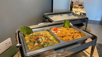 Un buffet proposant divers plats, notamment du riz, une soupe de légumes et un plat de viande.