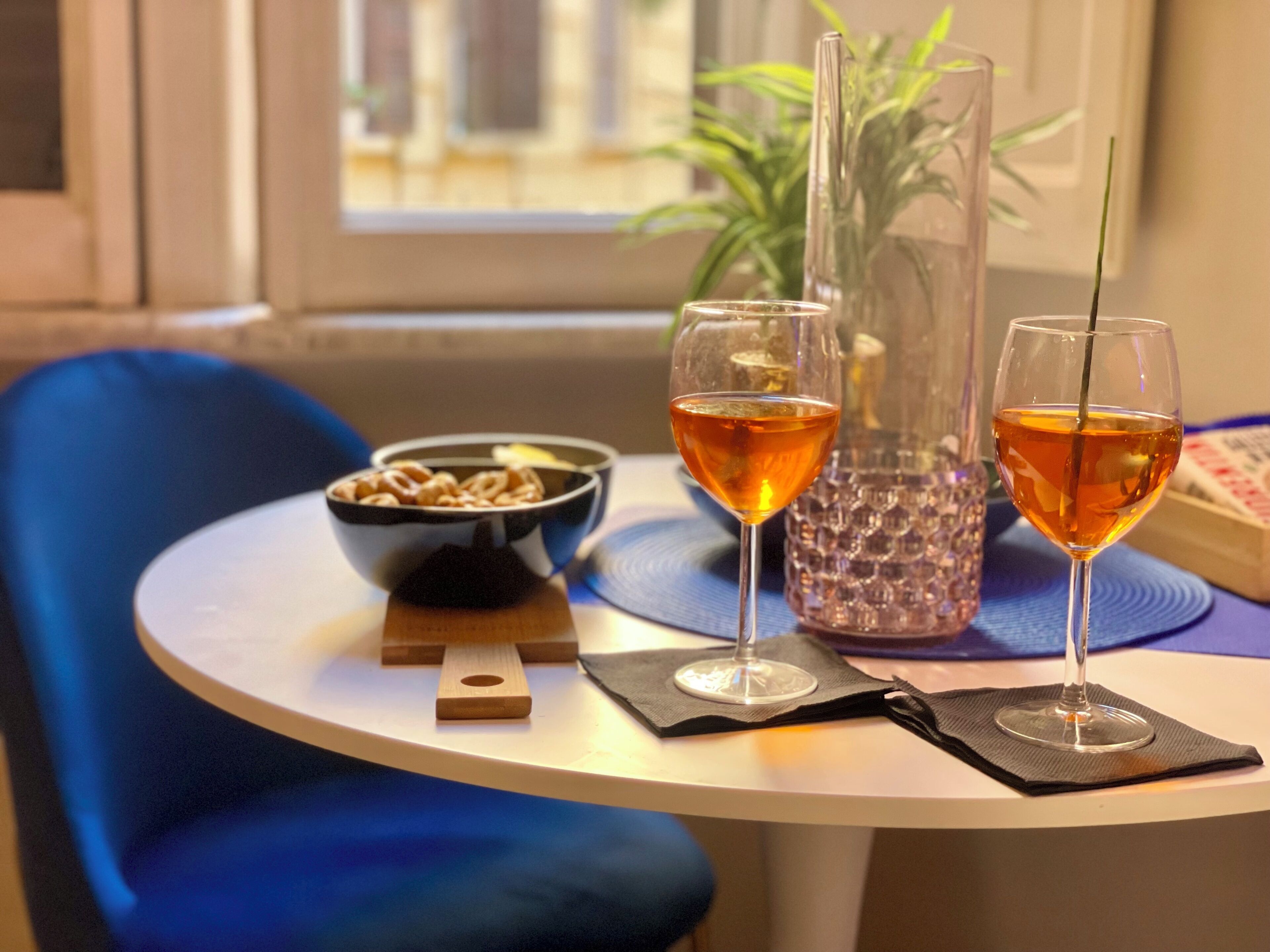 Un tavolo con due bicchieri di liquido ambrato, una ciotola di cereali e un vaso decorativo.