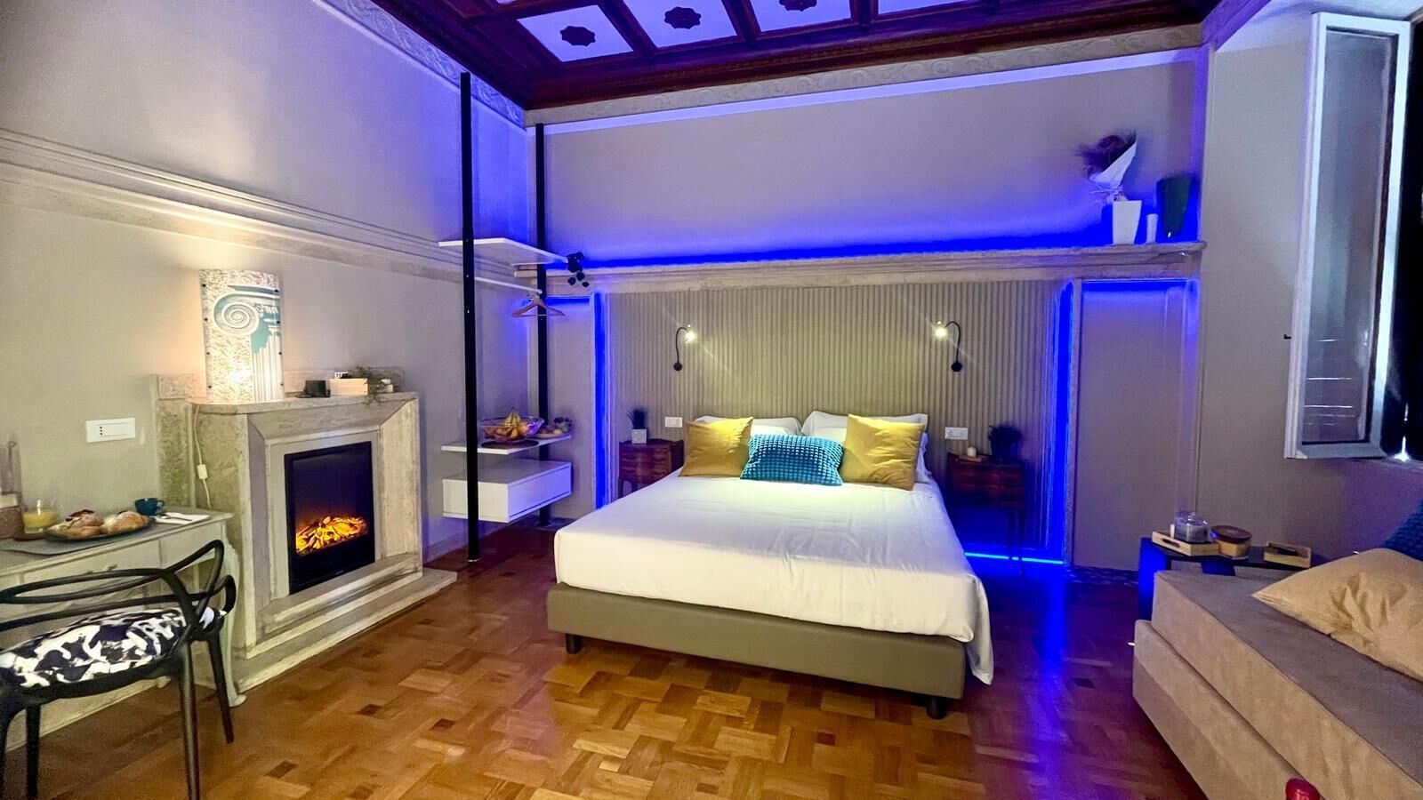 Un dormitorio moderno con chimenea, una cama con muchas almohadas, un escritorio con silla y una lámpara colgante.