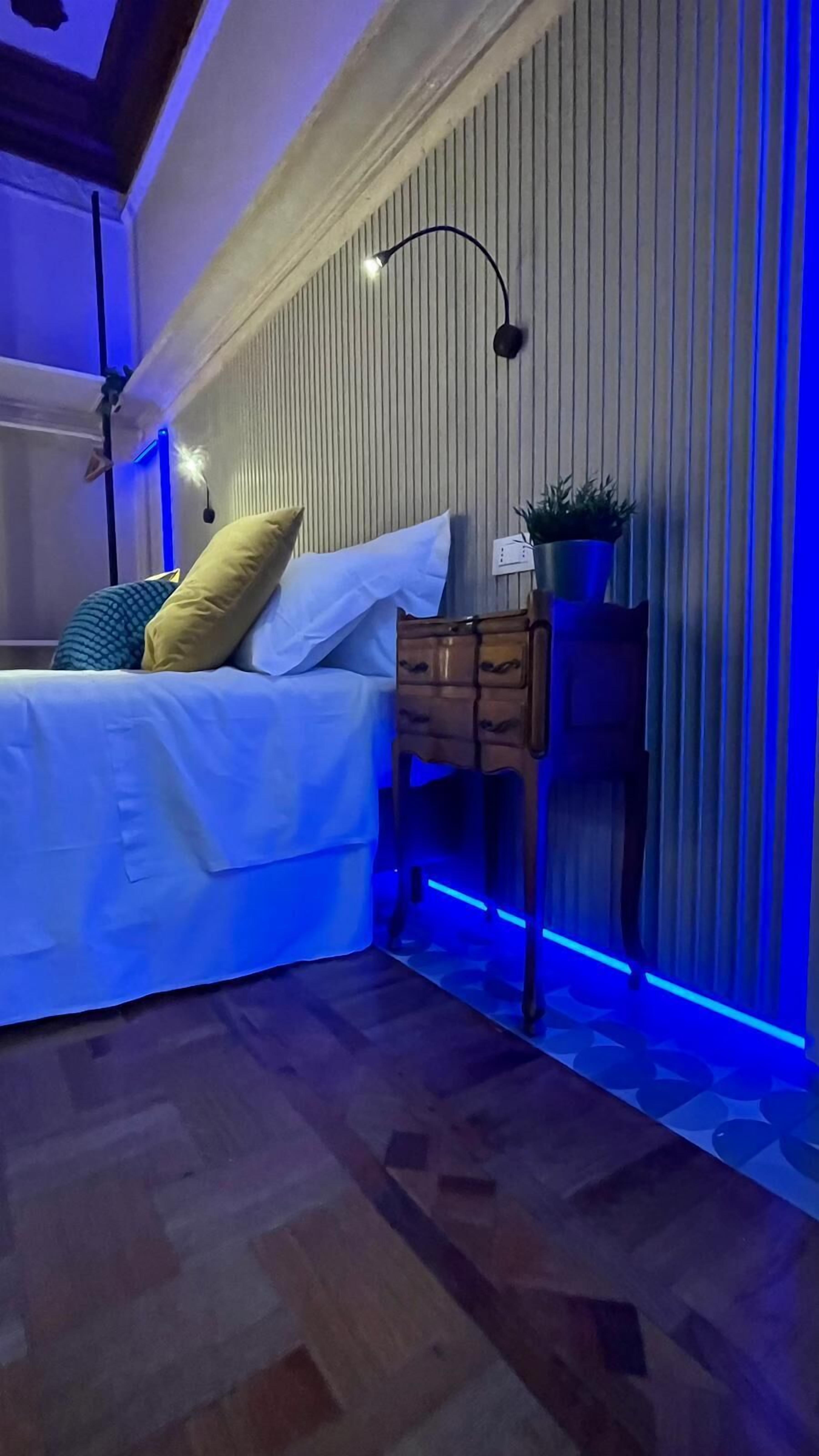 Een slaapkamer met een bed, nachtkastje en een wandlamp.