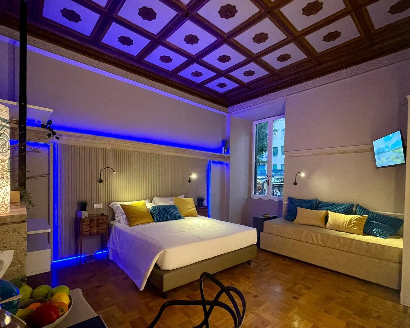 Quarto moderno com uma cama grande, um sofá, uma televisão e uma janela.