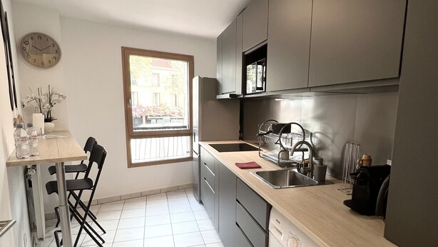 Une cuisine moderne équipée d’un lave-linge, d’un évier et d’une fenêtre.