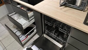 Une cuisine moderne équipée d’un lave-vaisselle encastré, d’une plaque de cuisson à induction noire et d’un égouttoir à vaisselle.