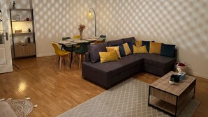 Un salon moderne avec un canapé d’angle, une table à manger et un lampadaire.