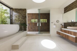 Une salle de bain moderne avec une grande baignoire, une douche à parois de verre et un meuble-lavabo en bois.