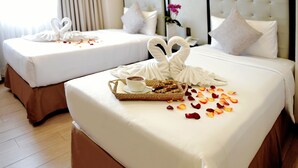 Two neatly made beds with white linens, a tray with a cup and pastries, and rose petals scattered on the bed. - Aura One Hotel (Baguio)