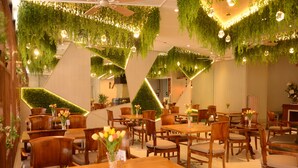 A restaurant with wooden tables and chairs, hanging plants, and pendant lighting. - Aura One Hotel (Baguio)