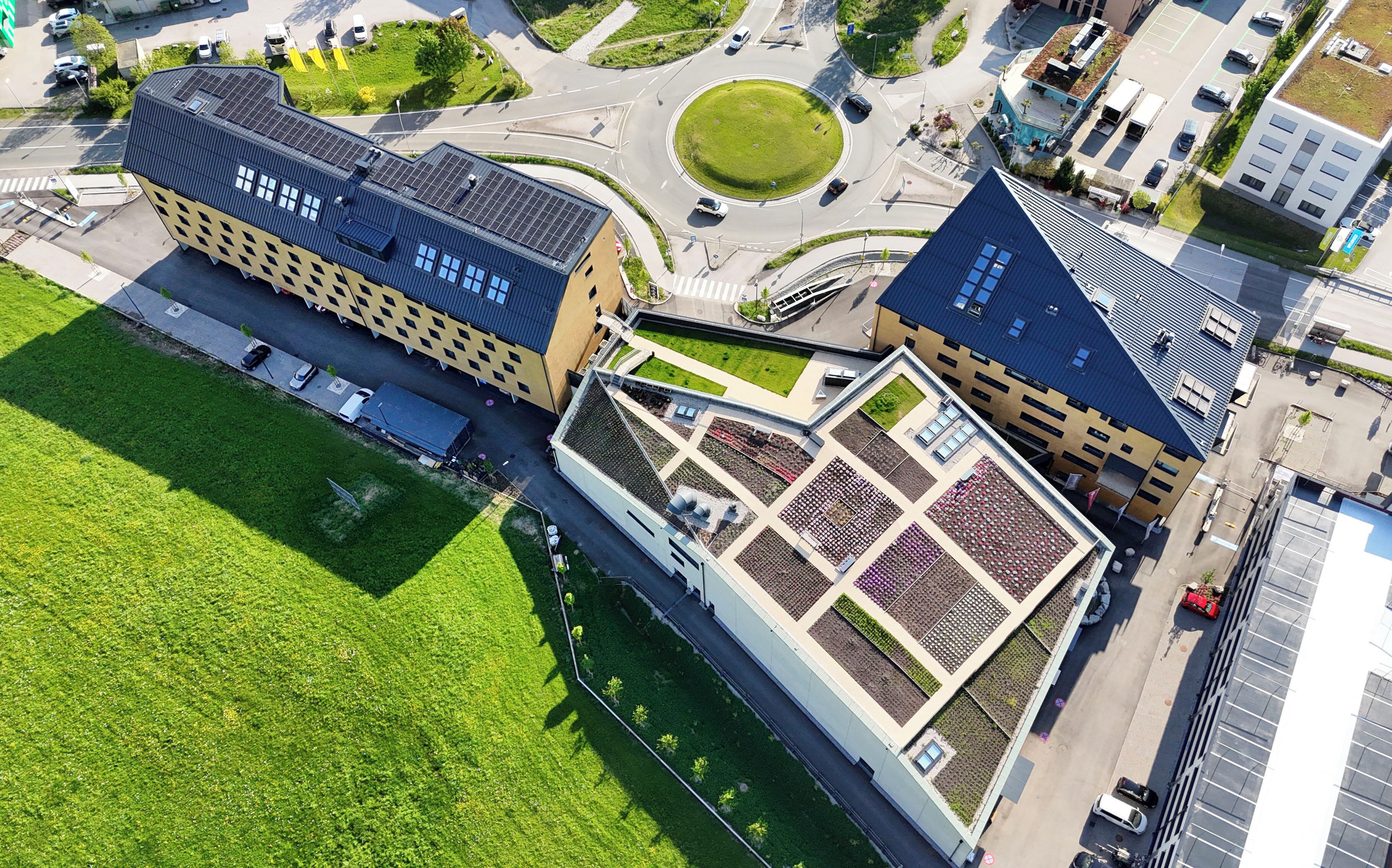 Vista aérea de un edificio con jardín en la azotea y aparcamiento.