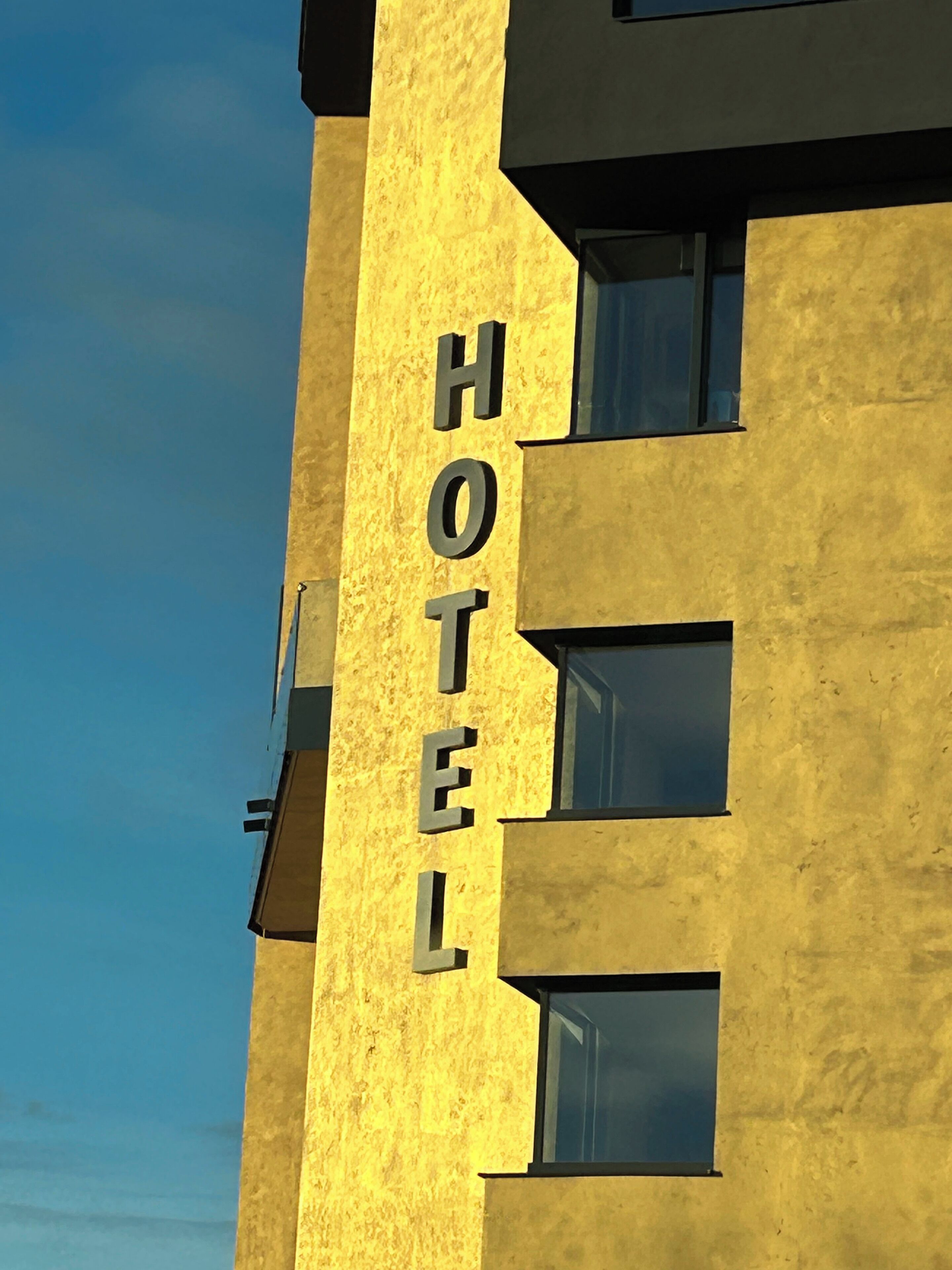 Een gebouw met een bord waarop 'HOTEL' staat, tegen een gele gevel.