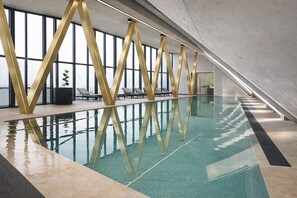 An indoor swimming pool with a modern design, including a unique golden structure and lounge chairs. - Hotel im Zentrum für Visionen (Puch bei Hallein)