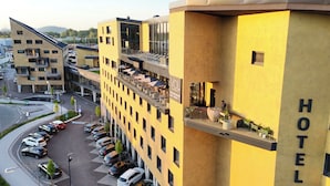Un hôtel à la façade jaune, doté de nombreux balcons et d’un bar situé sur le toit.