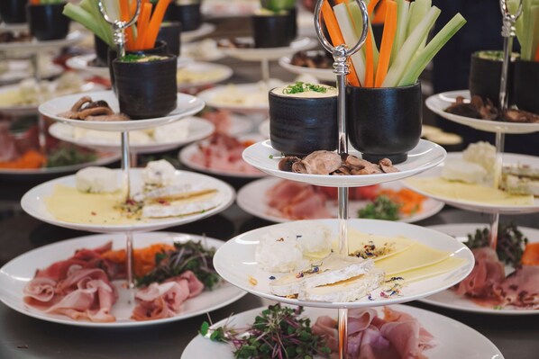 Un buffet proposant une variété de plats présentés sur différents plateaux, notamment des viandes, des fromages et des légumes.