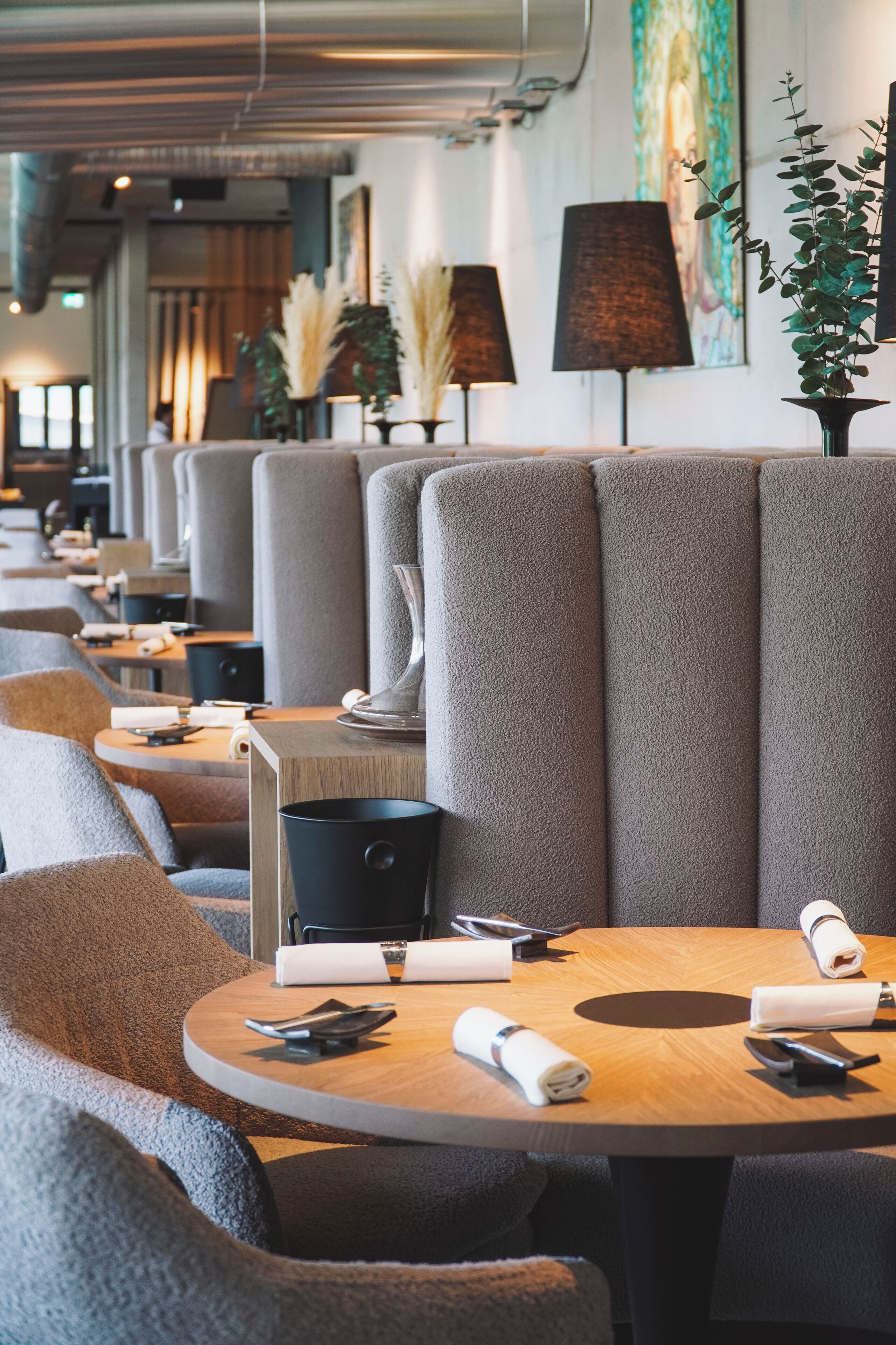 Un restaurante moderno con asientos tipo cabina, mesas redondas y una decoración limpia y minimalista.