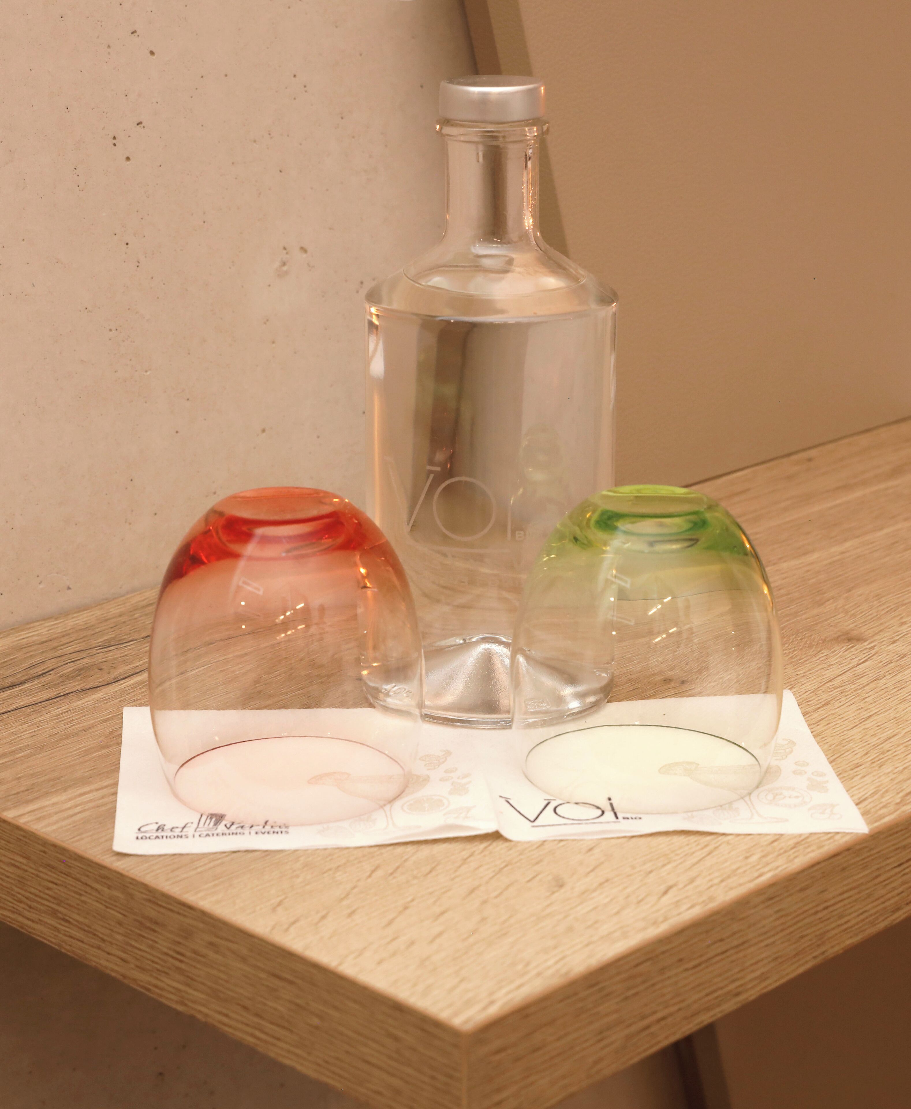 Three glass bottles on a wooden surface with a napkin underneath.