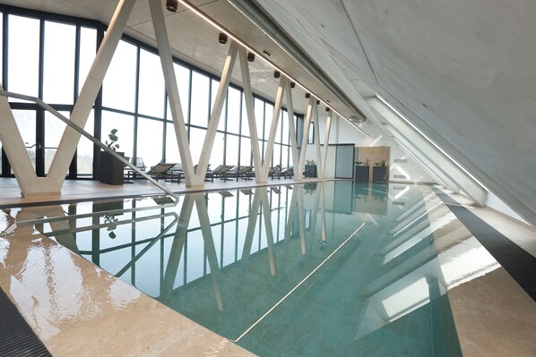 Una piscina techada, sillones reclinables de piscina