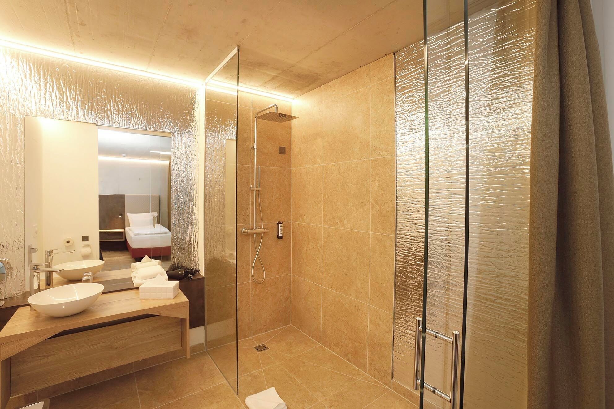 Un baño moderno con cabina de ducha de vidrio, tocador de madera con lavabo y un espejo grande.