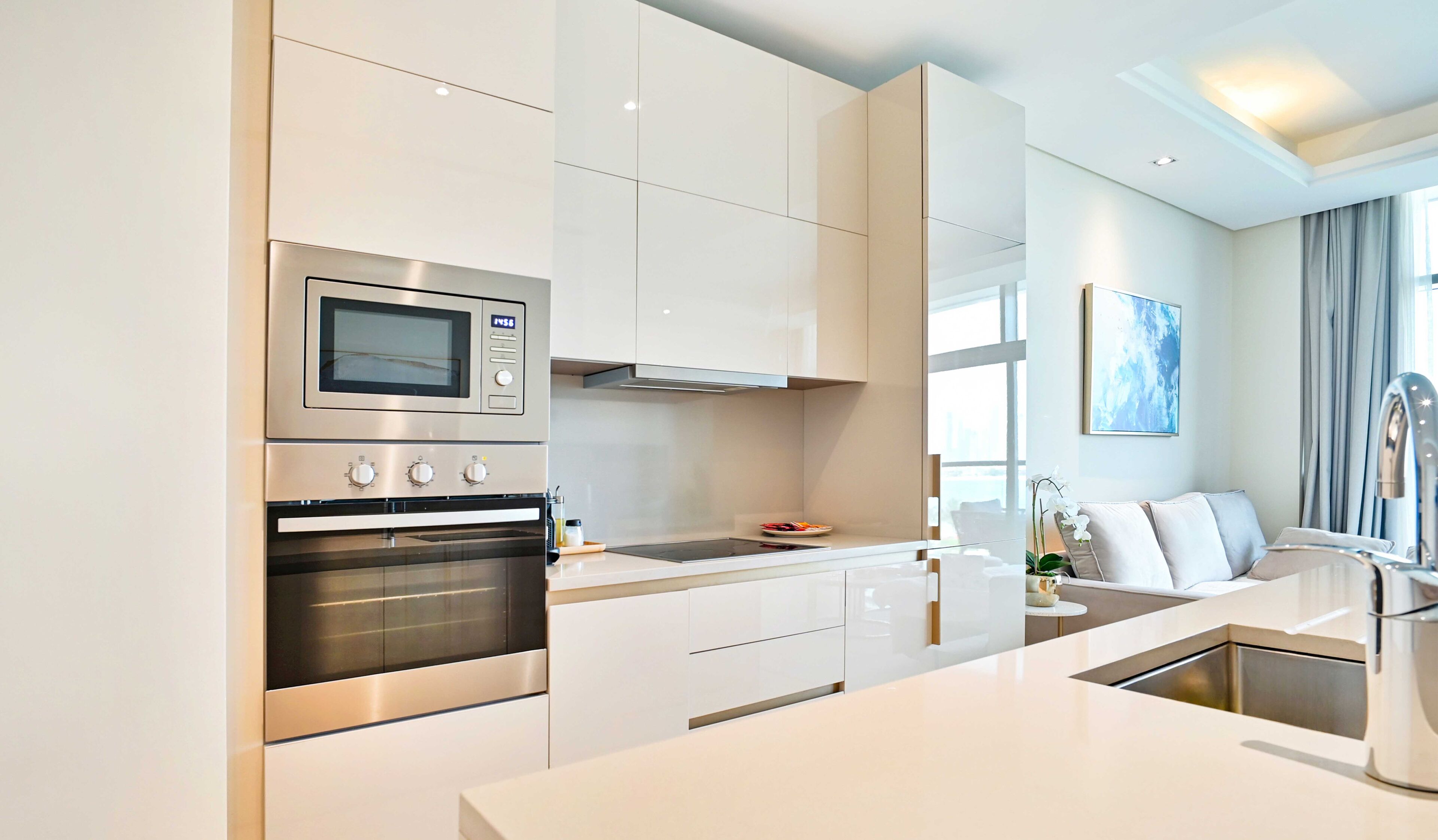 Une cuisine moderne dotée d’appareils électroménagers en acier inoxydable, de meubles blancs et d’un design minimaliste.