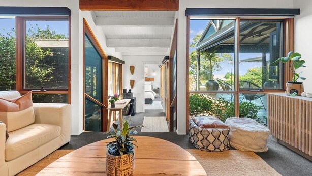 Un interior moderno con ventanas amplias, una mesa de centro de madera y un sofá.