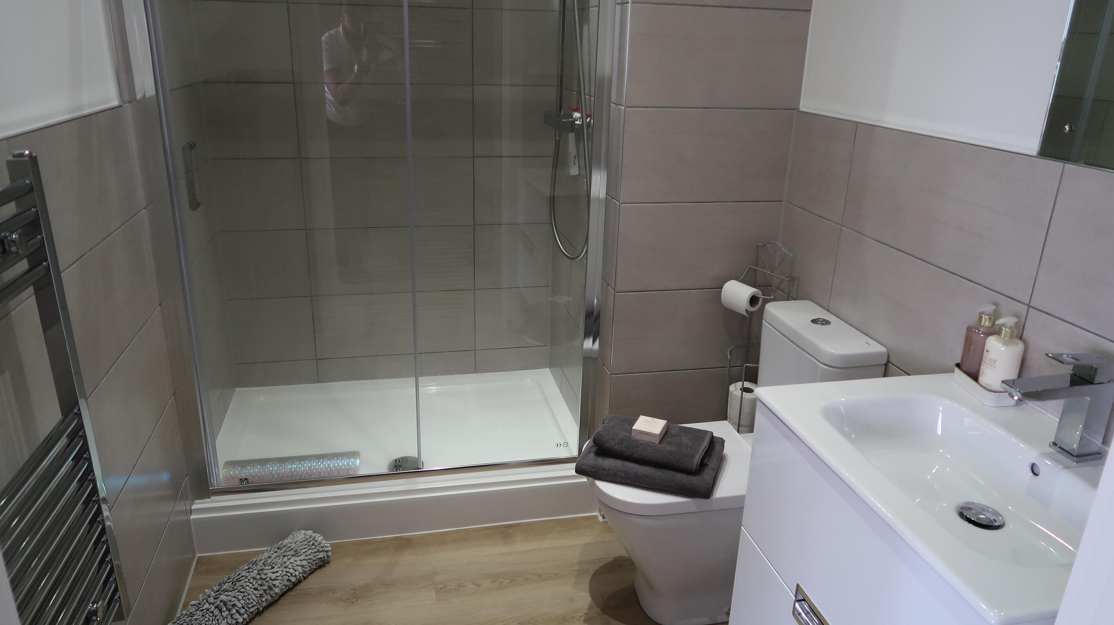 A bathroom with a glass-enclosed shower, a toilet, and a sink.