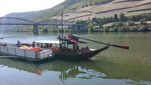 A boat docked at a river with a bridge in the background. - Casa da Trigueira (Alijó)