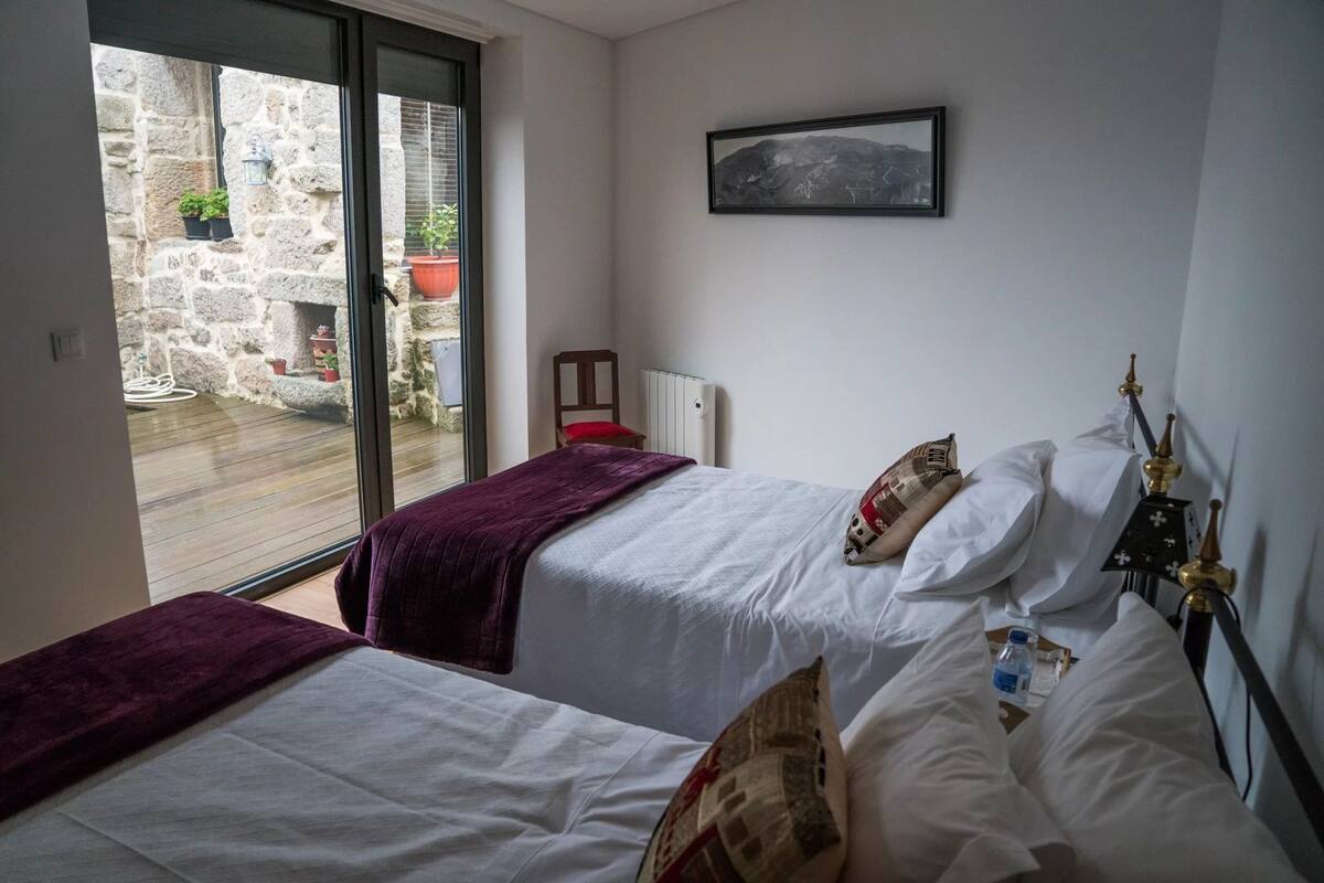 Ein Hotelzimmer mit zwei Betten, Blick auf den Innenhof, einem Heizkörper und einem gerahmten Bild an der Wand.