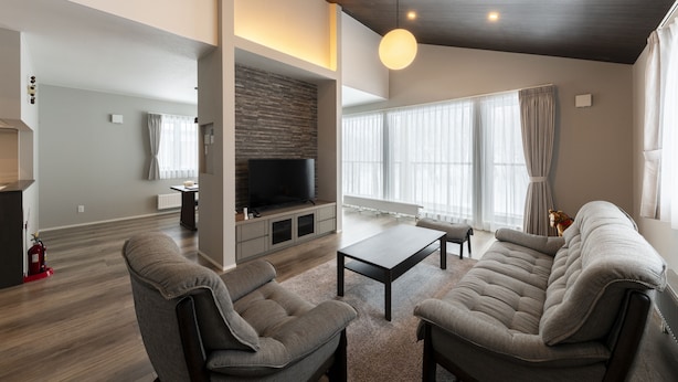 Een moderne woonkamer met een open haard, een televisie en een groot raam met gordijnen.