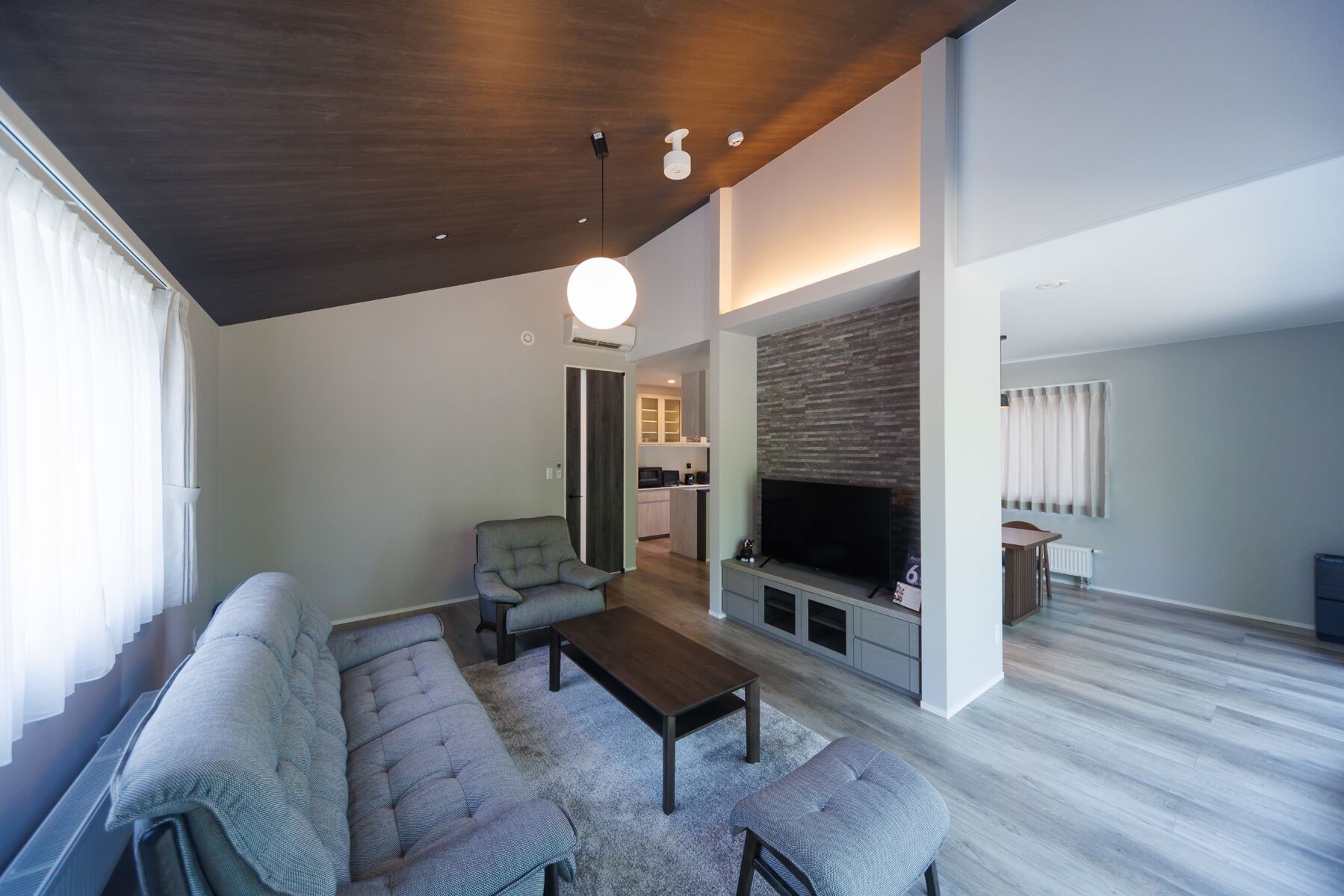 A modern living room with a sectional sofa, a coffee table, a flat-screen TV, and a fireplace.