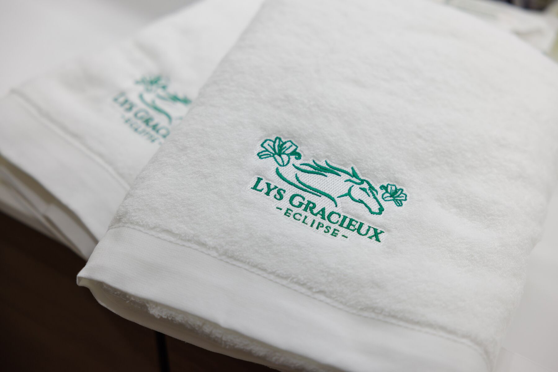 Folded white towels with embroidered logos and text.