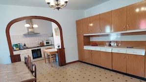 A kitchen with wooden cabinets, a tiled floor, and a dining table with chairs.