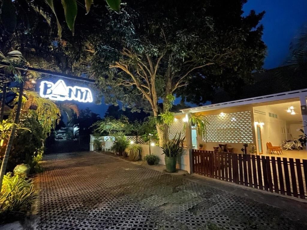 A well-lit entrance with a neon sign, paved pathway, and a wooden fence.