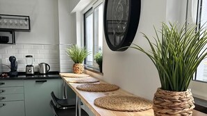 A modern kitchen with a long wooden bar counter, black bar stools, and a potted plant. - Malpique Guest House & Jacuzzi (Albufeira)